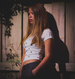 Portrait of young woman standing against wall