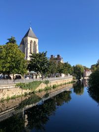 Canal amidst buildings against clear blue sky