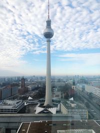 Communications tower in city against sky