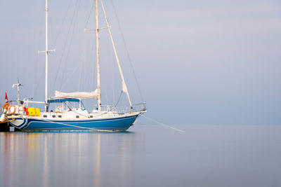 Sailboats moored on sea against sky