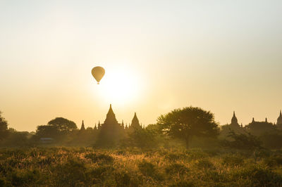 Hot air balloons on field against sky during sunset