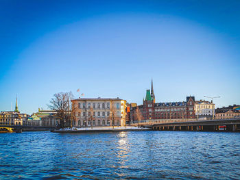 River by buildings against blue sky