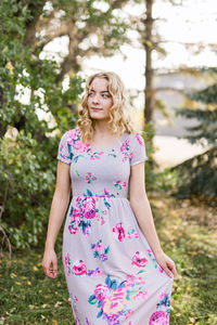 Portrait of young woman standing against trees