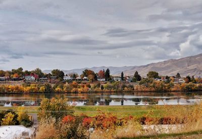 Scenic view of lake by buildings against sky