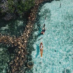 People relaxing on hammock over sea