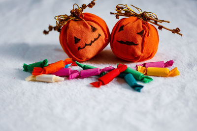 Close-up of pumpkin handmade decoration and colorful candies on table