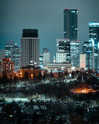 Illuminated buildings in city against sky at night