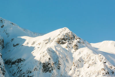 Scenic view of snowcapped mountains against clear blue sky