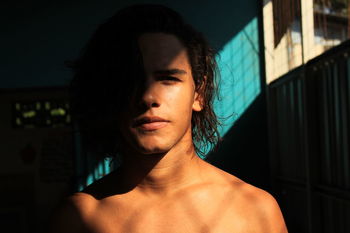 Sunlight falling on shirtless young man at home