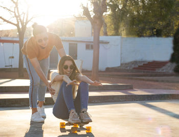 Funny couple laughing and playing with their longboards pushing each other 