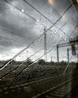 Close-up of wet window against sky
