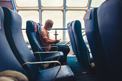 Man using mobile phone while sitting in bus