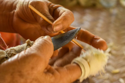 Cropped hands of craftsperson holding knife at workshop