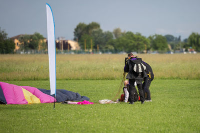 People with parachute on grassy field