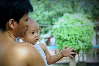 Shirtless father with son outdoors