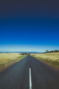 Empty road against clear blue sky