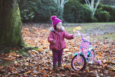 Full length of girl with bicycle standing in park