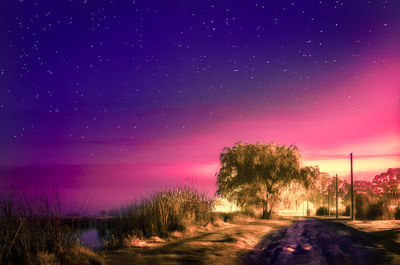 Road amidst field against sky at night