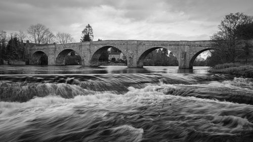 Arch bridge over river against sky