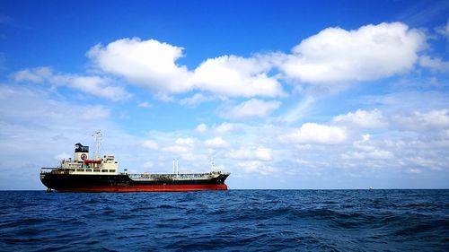 Boats in sea against cloudy sky