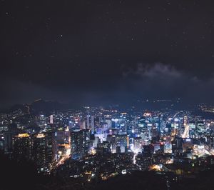 Illuminated cityscape against star field sky at night