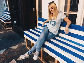 Thoughtful young woman looking down while sitting on bench