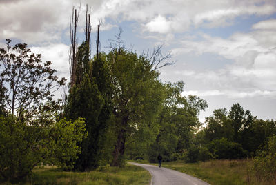 Road passing through landscape against cloudy sky