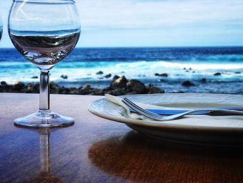 Close-up of wine glass on table at beach