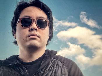 Portrait of young man wearing sunglasses against sky