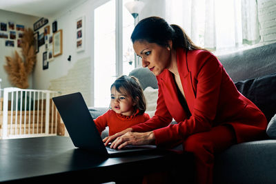 Young executive woman working from home while taking care of her young daughter