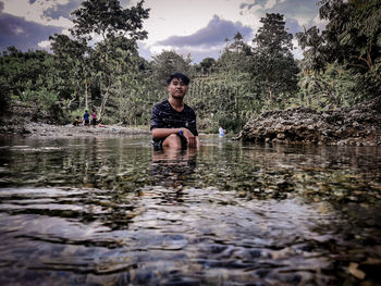 Portrait of man in lake against trees in forest