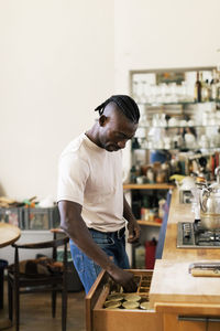 Male architect searching in drawer of kitchen counter while standing at home office