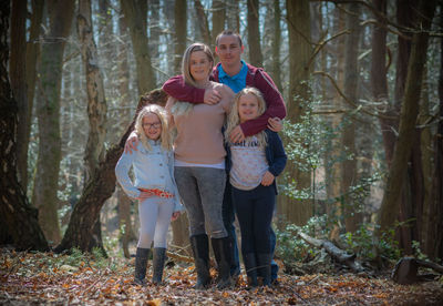 Full length portrait of cute girl standing by trees in forest