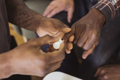 Cropped image of male caregiver applying nail polish to senior man at retirement home