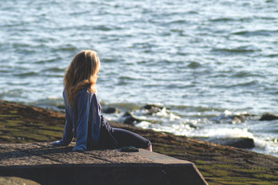 Rear view of woman sitting on beach