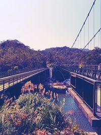Bridge over river by city against clear sky