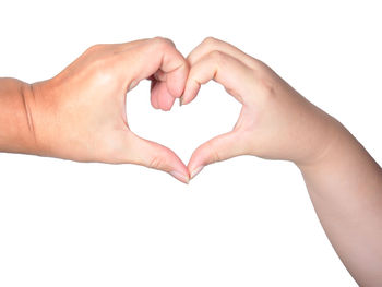 Close-up of hands making heart shape against white background