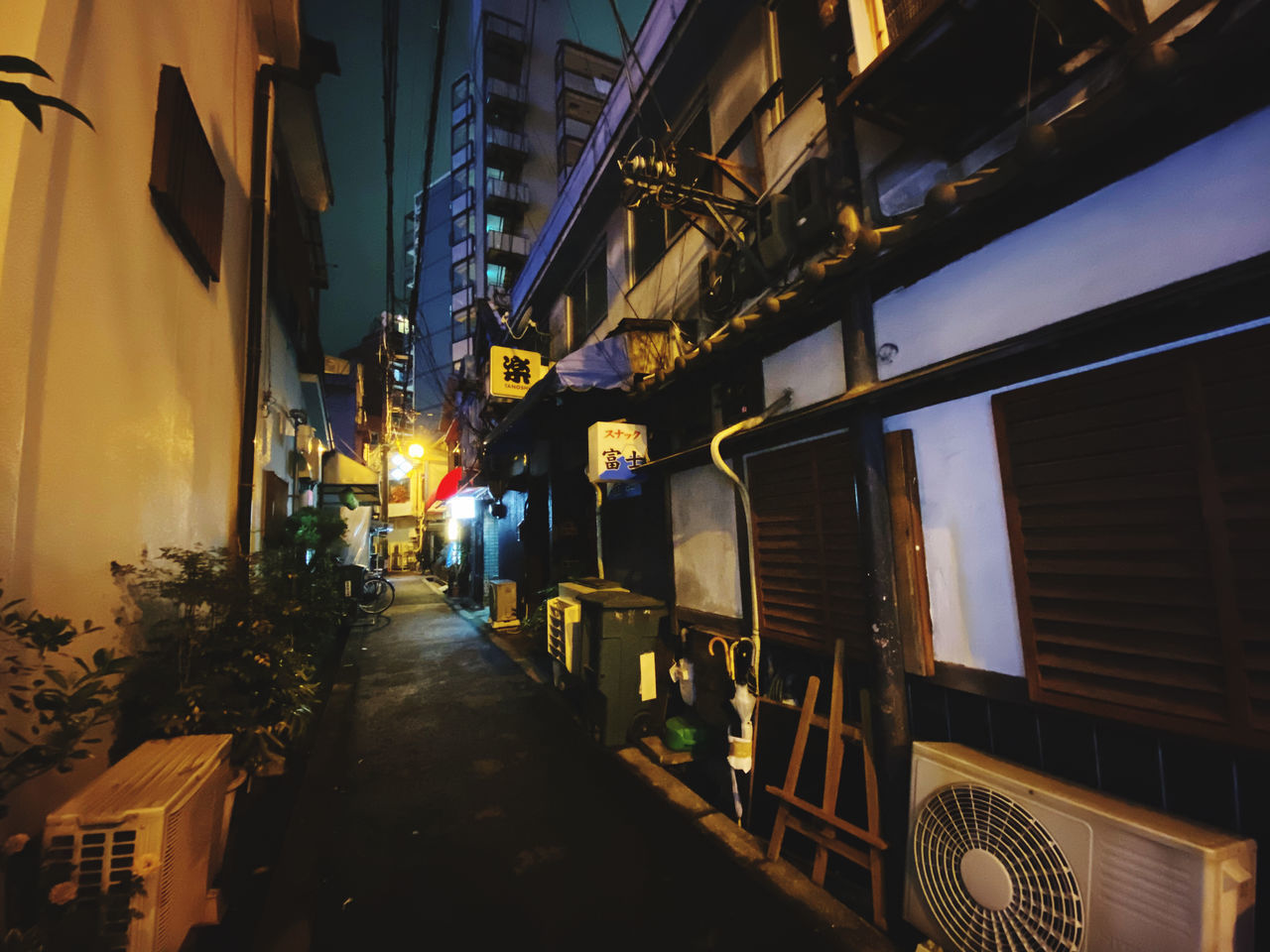 ILLUMINATED STREET AMIDST BUILDINGS IN CITY