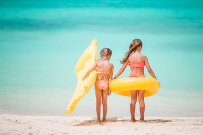 Rear view of sisters standing on beach