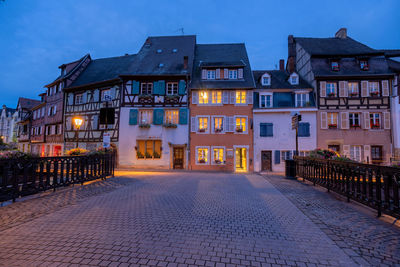 Illuminated street amidst buildings at night