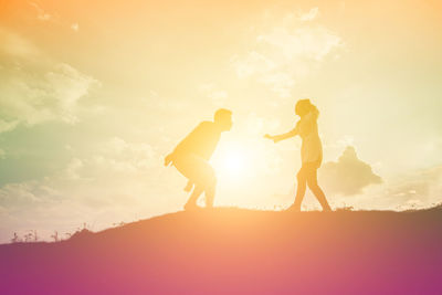 Silhouette people standing against sky during sunset