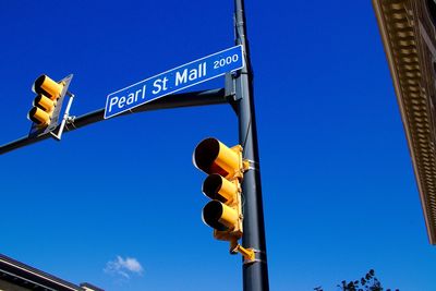 Low angle view of road sign against clear blue sky