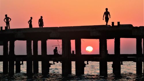 Silhouette people standing on pier against clear sky during sunset