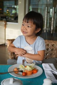 Smiling cute girl eating food at home