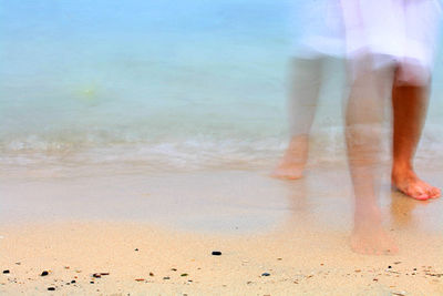 Low section of people walking on beach