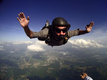 Young man skydiving in mid-air against sky