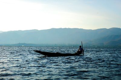 Man on boat in sea against sky