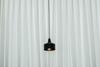 Close-up of illuminated light bulb against white wall