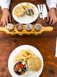 Cropped image of person having beer with burger and french fries on table