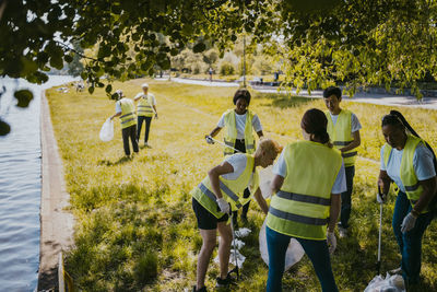 Female and male climate activists cleaning plastics at lakeshore